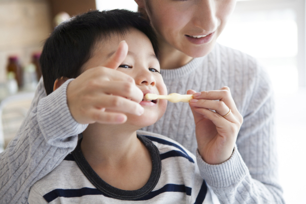 親が子供の歯磨きをしている画像